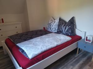 uma cama com lençóis pretos e brancos e um cobertor vermelho em Wiesenblick em Dönschten
