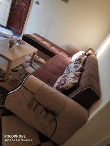 a brown couch sitting in a living room next to a table at شقة كلاسيك بمساحة خضراء قريبة من الحصري in 6th Of October
