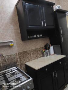 a kitchen with black cabinets and a stove at شقة كلاسيك بمساحة خضراء قريبة من الحصري in 6th Of October