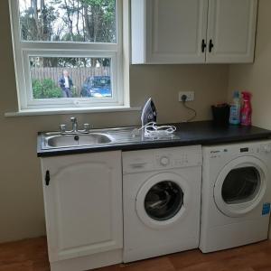 een keuken met een wastafel en een wasmachine bij Suaimhneas in Falcarragh