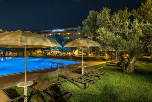 a pool with umbrellas and lounge chairs next to a building at Rada Siri in Montepaone