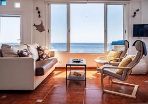 a living room with a couch and chairs and the ocean at Canary casita next to the Atlantic Ocean in Radazul
