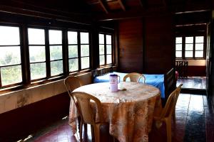 a dining room with a table and chairs and windows at Balekhan Homestay - Heritage & Mountain View in Chikmagalur