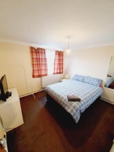 a bedroom with a bed with a blue plaid blanket at 4 Bedroom Thundersley Apartment in Rayleigh