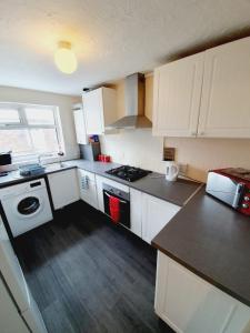 a kitchen with white cabinets and a stove top oven at 4 Bedroom Thundersley Apartment in Rayleigh