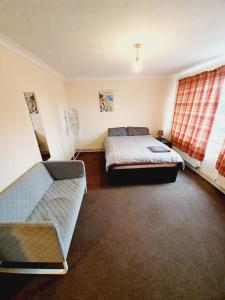 a bedroom with two beds and a couch in it at 4 Bedroom Thundersley Apartment in Rayleigh