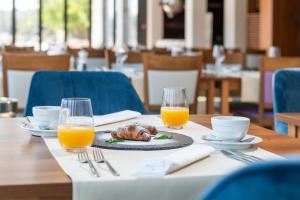 a table with a plate of food and two glasses of orange juice at Ribarska Koliba Resort in Pula
