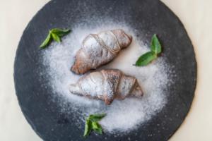 two croissants on a plate with powdered sugar at Ribarska Koliba Resort in Pula