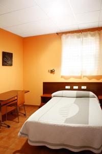 um quarto com uma cama, uma mesa e uma janela em Alojamiento Numancia Pensión em Burgos