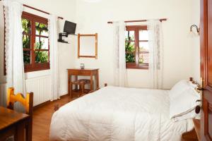 a bedroom with a white bed and two windows at Elatos Country House in Portaria