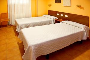 Cette chambre d'hôtel comprend 3 lits avec des draps blancs. dans l'établissement Alojamiento Numancia Pensión, à Burgos