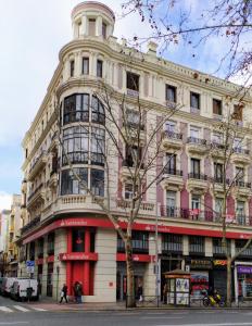 a large building on a street with a tree at Hostal Abitum Madrid in Madrid