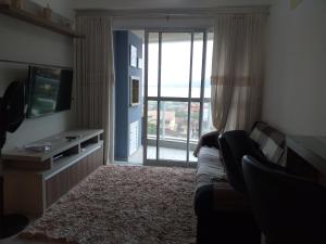 sala de estar con sofá y puerta corredera de cristal en Apartamento Família Santos, en Penha