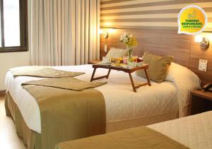 a hotel room with two beds with a table on it at Hotel Continental Business - 200 metros do Complexo Hospitalar Santa Casa in Porto Alegre
