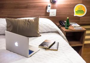 a laptop computer sitting on a bed with a table at Hotel Continental Business - 200 metros do Complexo Hospitalar Santa Casa in Porto Alegre