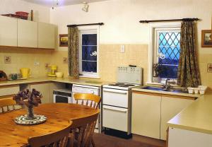 cocina con mesa, fregadero y fogones en Pekes Tudor View en Hailsham