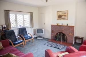 sala de estar con chimenea de ladrillo y 2 sillas en Pekes Tudor View en Hailsham