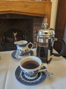 a cup of coffee sitting on a table with a coffee pot at The Sycamore Guest House in York