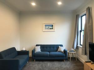 a living room with two blue couches and a tv at Te Waiharakeke Holiday Home in Blenheim