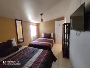 a bedroom with two beds and a flat screen tv at La Vid Posada Inn in Valle de Guadalupe