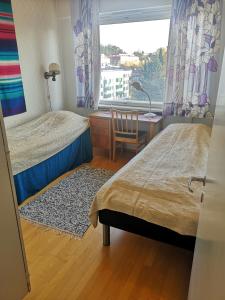 1 Schlafzimmer mit 2 Betten, einem Schreibtisch und einem Fenster in der Unterkunft Apartment Vuorikatu 35 Mummola in Kuopio