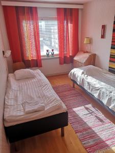 a bedroom with two beds and a window with red curtains at Apartment Vuorikatu 35 Mummola in Kuopio