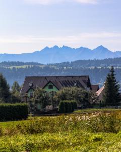 a house in a field with mountains in the background at Zajazd Czorsztyński in Maniowy