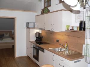- une cuisine avec des placards blancs et un évier dans l'établissement Gästehaus Gaisalpe, à Fischen im Allgäu