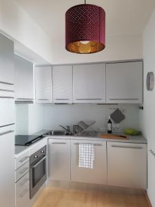 cocina con armarios blancos y luz colgante en Lagos Marina Side Apartment, en Lagos