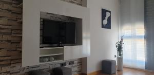 a living room with a tv on a brick wall at Apartamento tranquilo, amante de la naturaleza in Ponferrada