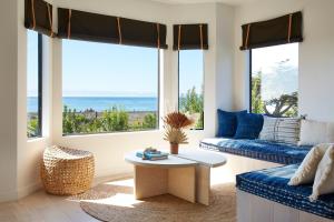 uma sala de estar com um sofá, uma mesa e janelas em White Water em Cambria