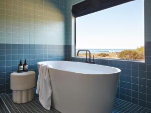 a bath tub in a blue bathroom with a window at White Water in Cambria
