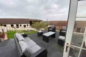 eine Terrasse mit einem Sofa, Stühlen und einem Tisch in der Unterkunft Charming apartment with hot tub , Viewly Hill Farm in Norton