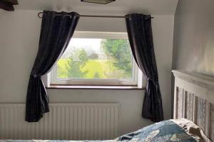 a window with black curtains in a bedroom at Charming apartment with hot tub , Viewly Hill Farm in Norton