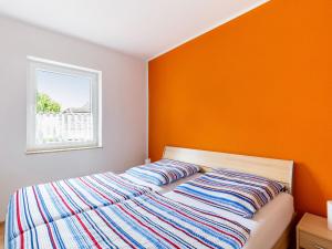 ein Bett in einem Schlafzimmer mit einer orangefarbenen Wand in der Unterkunft Modern Apartment in Wismar near Baltic Sea in Wismar