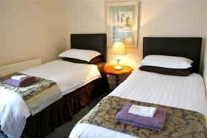Cette chambre comprend deux lits et une table avec une lampe. dans l'établissement Melrose Guest House, à Douglas