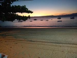 a beach with boats in the water at sunset at Nena's Suítes in Praia de Araçatiba