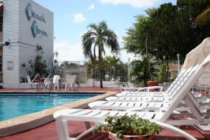 a group of white lounge chairs next to a swimming pool at Beach and Town Motel in Hollywood