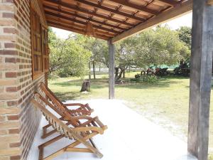 dwa drewniane krzesła siedzące na ganku domu w obiekcie Vila das Mangabeiras Corumbau w mieście Corumbau