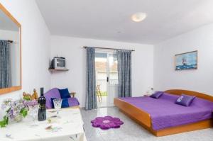 a bedroom with a purple bed and a table at Apartments Jaki - 150 m from beach in Orebić