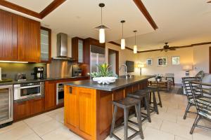 a kitchen with wooden cabinets and a island with bar stools at Ground floor unit with Private Garden in Kapolei
