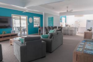 ein Wohnzimmer mit blauen Wänden und Sofas sowie eine Küche in der Unterkunft The Jetty House Jervis Bay in Myola