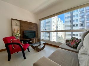 ein Wohnzimmer mit einem Sofa und einem großen Fenster in der Unterkunft Apto 2 dom e 3 quadras do mar edifício Silviane Gomes 7 andar in Capão da Canoa