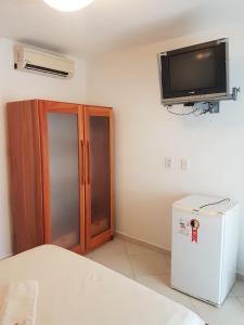 Zimmer mit einem TV an der Wand und einem Kühlschrank. in der Unterkunft Pousada Italia in Natal