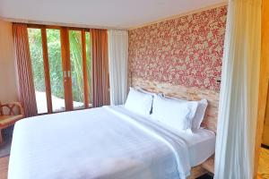 um quarto com uma cama branca e uma parede de janelas em Kadewa Retreat Ubud - Adults Only em Ubud