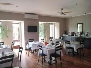 een eetkamer met witte tafels en stoelen bij Acacia Guest House in Nelspruit