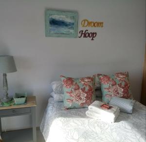 uma cama com almofadas e uma placa na parede em Froggy Bay is the best all the way! em Simonʼs Town