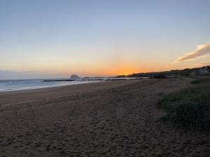 a beach with the sun setting in the distance at Breakwater in North Berwick +6 photos