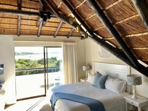 a bedroom with a bed with a view of the ocean at i-LOLLO Bed & Breakfast at the River Mouth in St Francis Bay