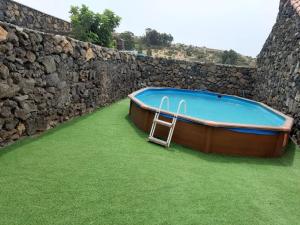 a small boat on the grass next to a stone wall at Caserio Los Partidos in San Jose De Los Llanos